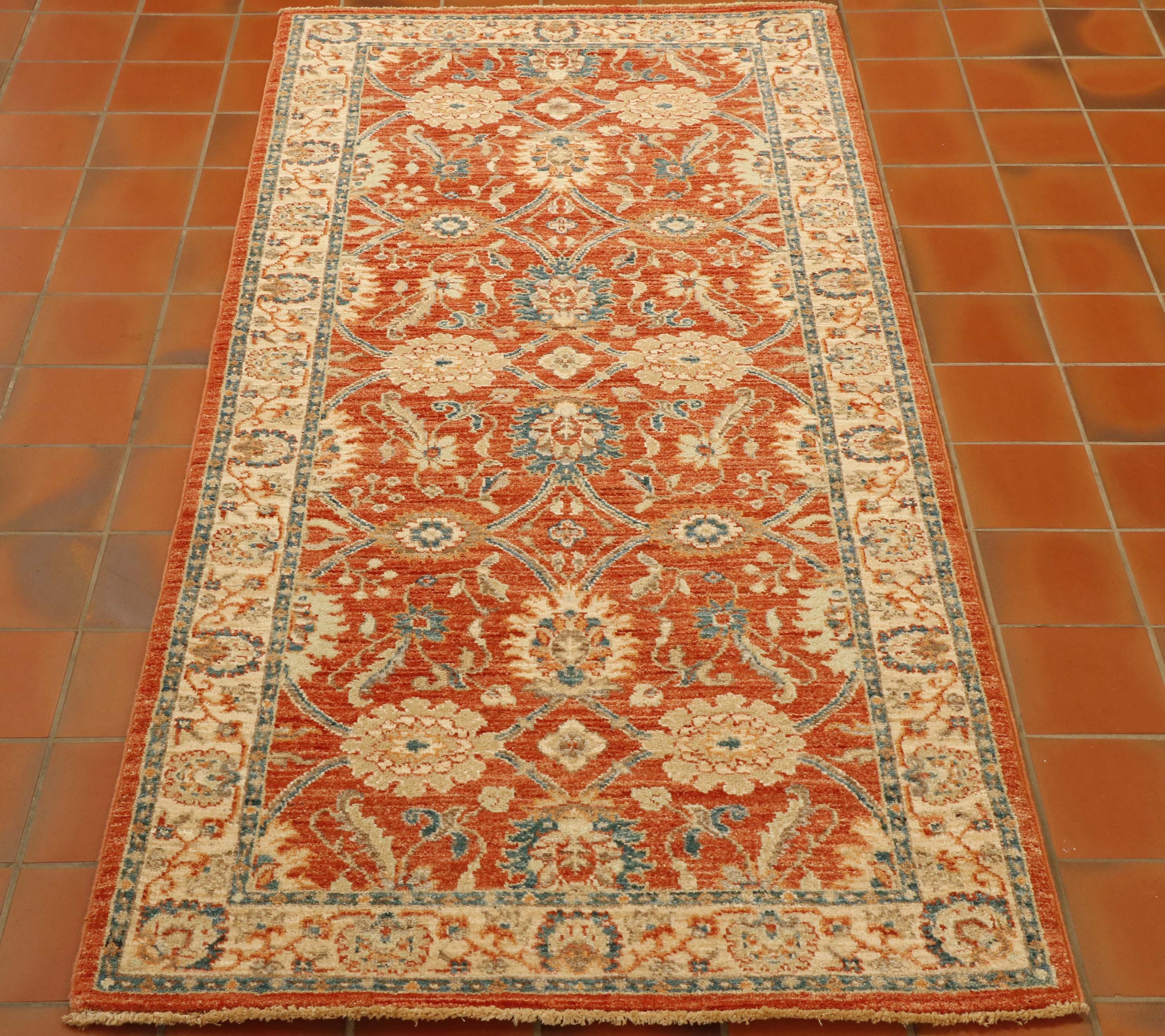 Soft terracotta ground with a blue and cream decoration of flora.  Cream border with similar floral design but using the terracotta and blue as the colour palette.  Soft green used for highlights. 